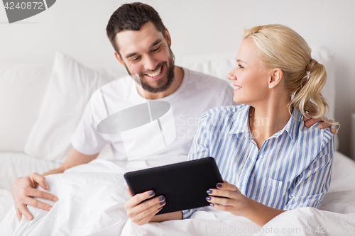 Image of smiling happy couple with tablet pc in bed at home