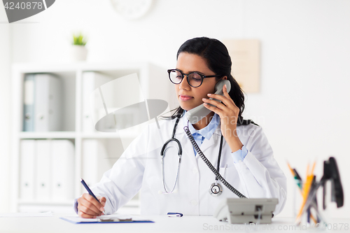 Image of doctor with clipboard calling on phone at hospital