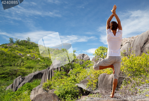 Image of young man making yoga tree pose outdoors