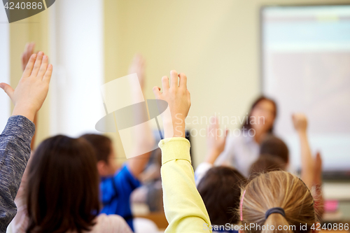 Image of group of school kids raising hands in classroom