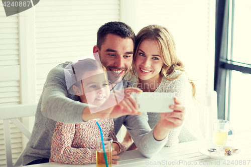 Image of happy family taking selfie at restaurant