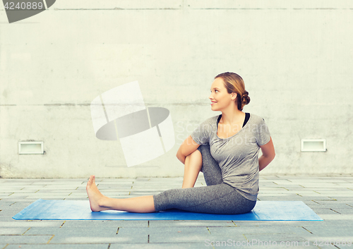 Image of woman making yoga in twist pose on mat