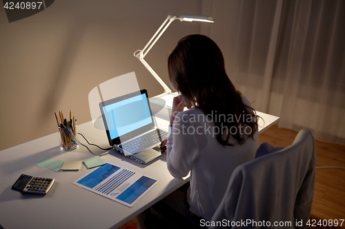 Image of businesswoman with laptop at night office