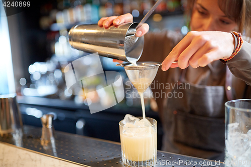 Image of bartender with cocktail shaker and glass at bar