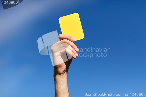 Image of referee on football field showing yellow card