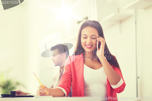 Image of businesswoman calling on smartphone at office