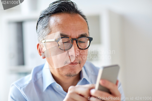 Image of businessman texting on smartphone at office