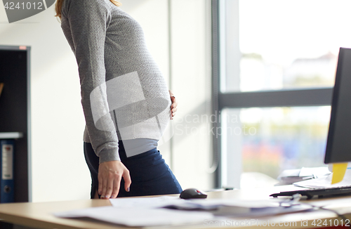 Image of pregnant businesswoman with computer at office
