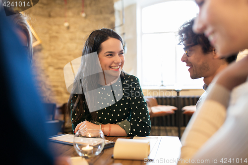 Image of happy friends with menu at restaurant