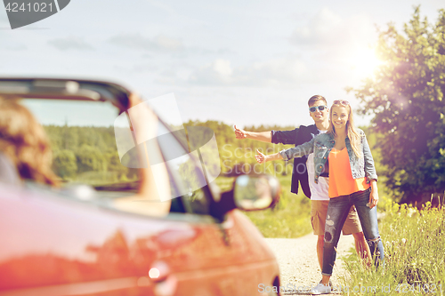 Image of couple hitchhiking and stopping car on countryside