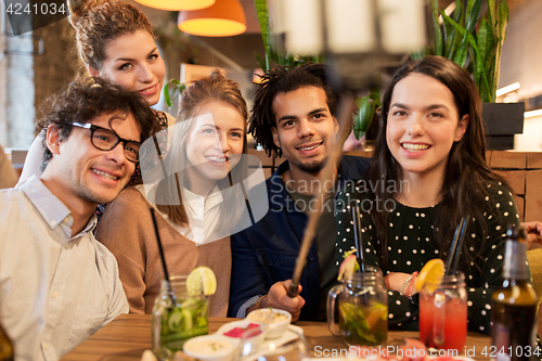 Image of friends taking selfie by smartphone at bar or cafe