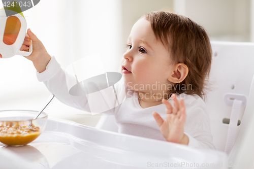 Image of baby drinking from spout cup in highchair at home