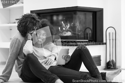 Image of multiethnic couple used tablet computer on the floor