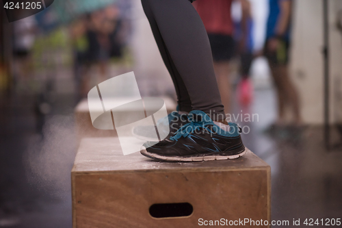 Image of black woman is performing box jumps at gym