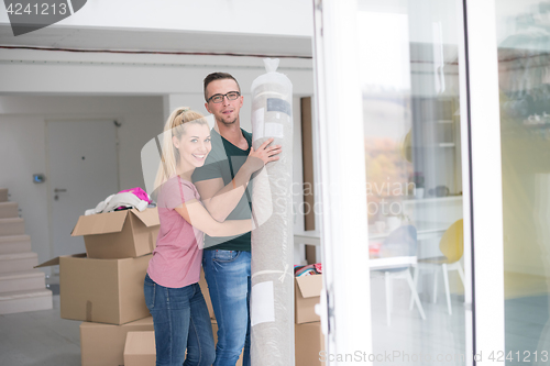 Image of couple carrying a carpet moving in to new home