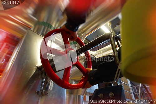 Image of industrial factory worker turning red wheel of valve