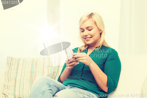 Image of happy woman with smartphone at home