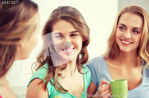 Image of happy young women drinking tea with sweets at home