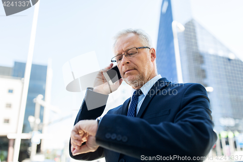 Image of senior businessman calling on smartphone in city