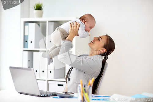 Image of happy businesswoman with baby and laptop at office