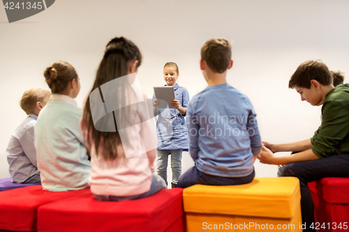Image of group of happy children with tablet pc at school
