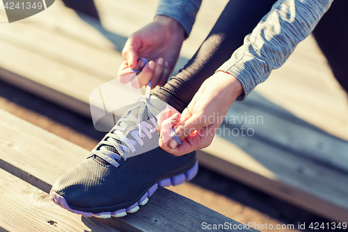 Image of close up of sporty woman tying shoelaces outdoors