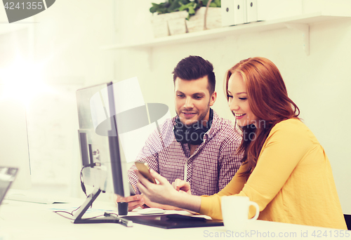 Image of smiling creative team with smartphones at office