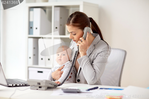 Image of businesswoman with baby calling on phone at office