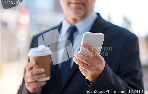 Image of senior businessman with smartphone and coffee