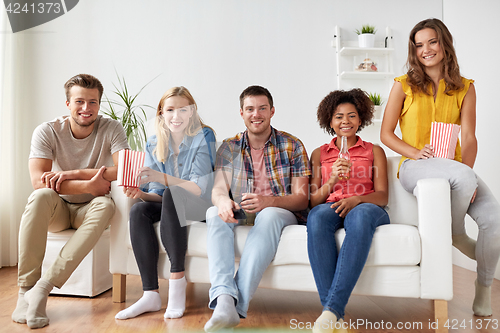 Image of happy friends with popcorn and beer at home