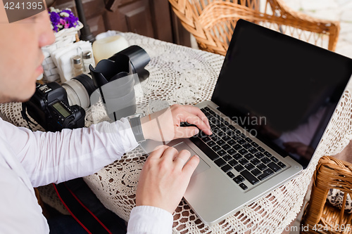 Image of Man working on laptop at the wooden table outdoors