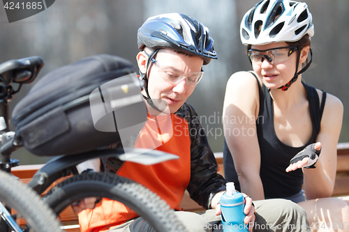 Image of Two cyclists resting on bench