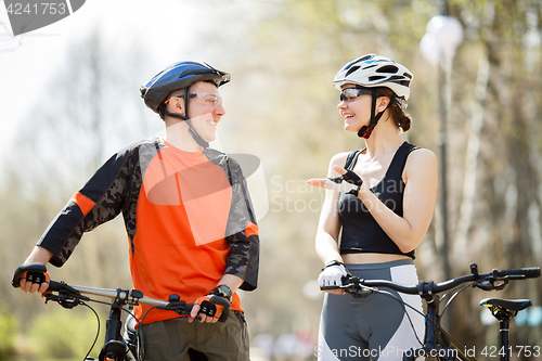 Image of Two bicyclists stand in park