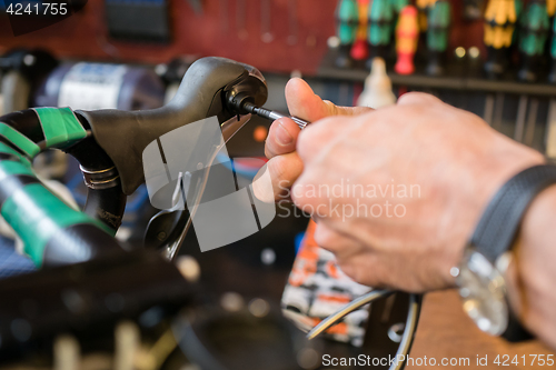 Image of Man repairs bicycle handle screwdriver