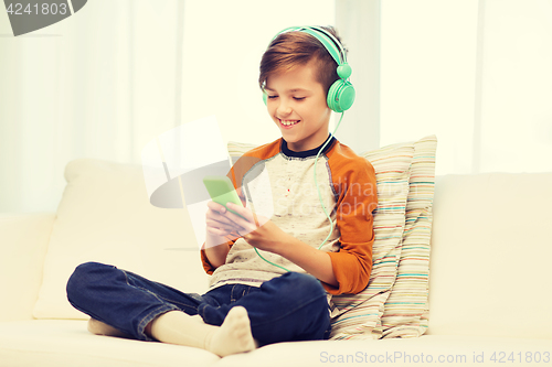 Image of happy boy with smartphone and headphones at home