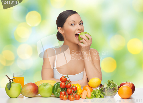 Image of woman with fruits and vegetables eating apple