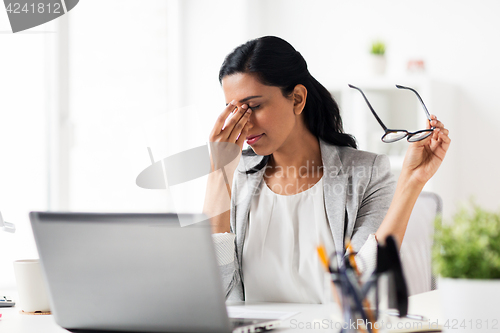 Image of businesswoman rubbing tired eyes at office