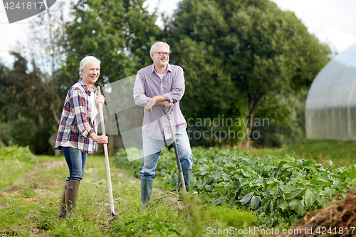 Image of senior couple with shovels at garden or farm