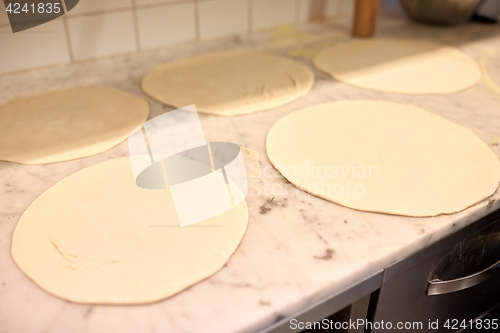 Image of raw pizza dough on table at pizzeria