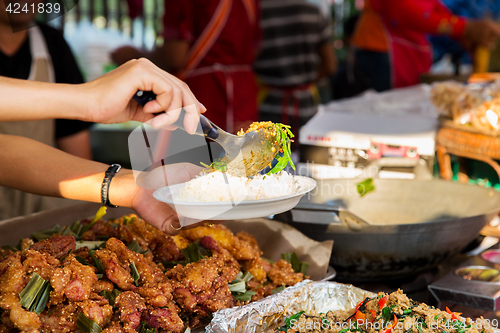 Image of seller with rice and wok food at street market