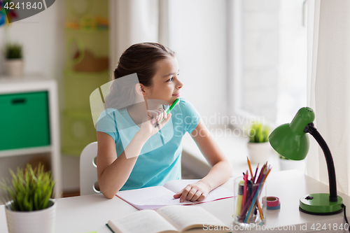 Image of happy girl with book writing to notebook at home