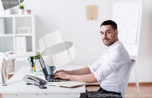 Image of happy businessman with laptop at office