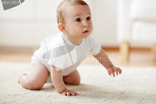 Image of little baby in diaper crawling on floor at home