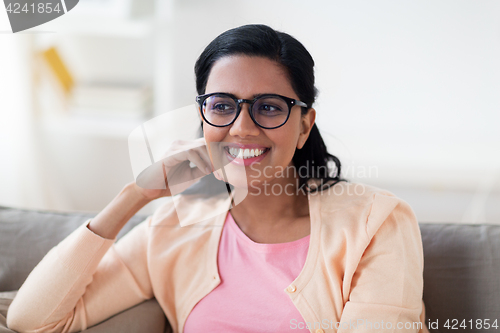 Image of happy smiling young woman sitting on sofa at home