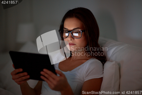 Image of woman with glasses and tablet pc in bed at home