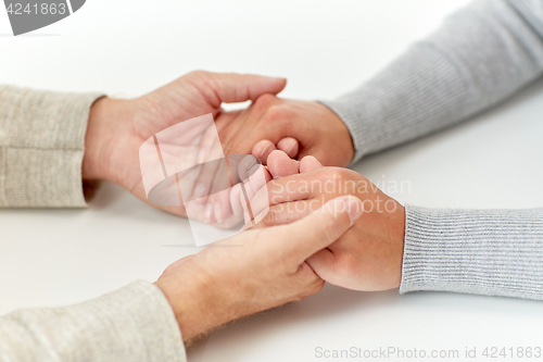 Image of close up of old man and young woman holding hands