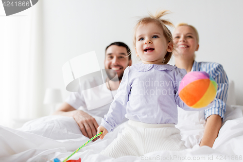 Image of happy child with toys and parents in bed at home