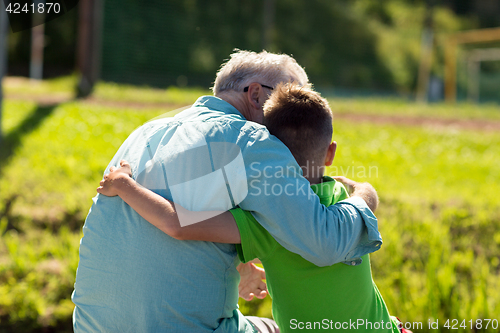 Image of grandfather and grandson hugging outdoors