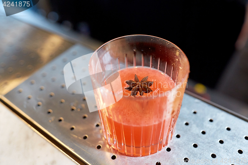 Image of glass of cocktail with anise at bar