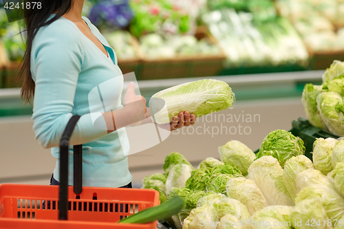 Image of woman with basket and chinese cabbage at grocery